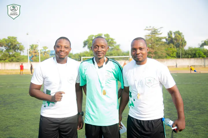 Trois encadrants souriants posent sur le terrain
